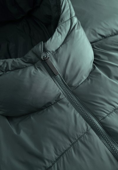 Veste matelassée vert foncé avec un col relevé et un zip central partiellement remonté.