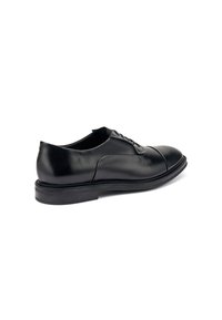 Scarpa da uomo nera in pelle con finitura liscia, punta arrotondata, lacci e suola bassa e solida. Dettagli di cucitura discreti vicino alla cappetta.