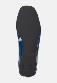 Suela de un zapato azul con una parte inferior de caucho negro texturizado y bordes curvados, mostrando detalles de diseño intrincados.