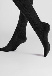 Schwarze knielange Socken mit strukturiertem Muster, ausgestattet mit Rippendesign und verstärktem Fersenbereich, die einen glatten Strickabschluss zeigen.