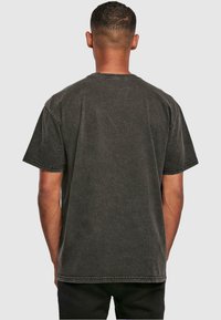 Dark gray cotton T-shirt, short sleeves, relaxed fit, visible stitching details, crew neck, and soft, worn texture. Back view shown.