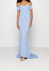 Světle modrá, off-the-shoulder večerní šaty s přiléhavým korzetem a rozšířenou sukní. Hladká látka s jemným leskem. Obsahuje výstřih ve tvaru srdce.