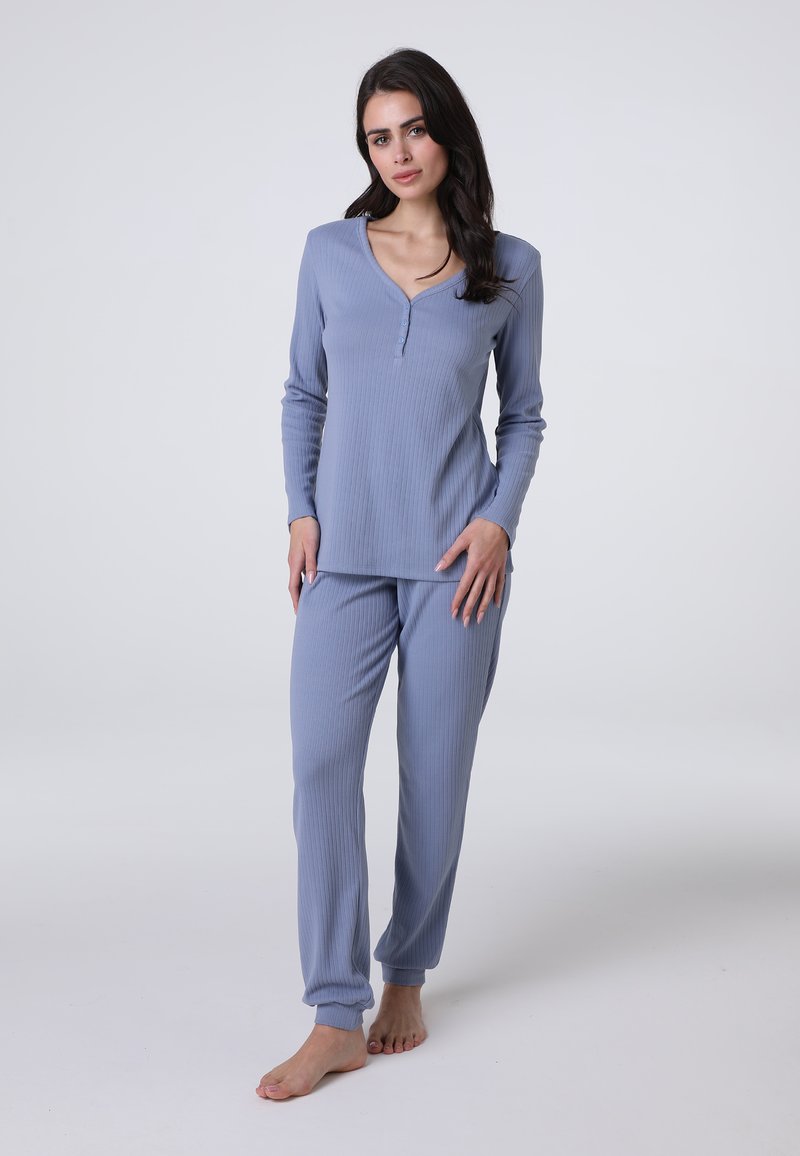 Completo pigiama a costine di colore azzurro chiaro, composto da una maglia a maniche lunghe con scollatura a V e dettaglio dei bottoni, abbinato a pantaloni taperizzati coordinati.