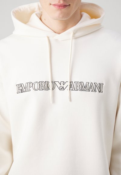 Felpa color crema realizzata in misto cotone, con un grande logo ricamato in nero "EMPORIO ARMANI" sul petto e cappuccio con lacci.