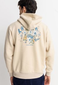 Sudadera beige con capucha ajustable que presenta coloridos gráficos florales y musicales en la parte posterior. Tela suave, corte holgado y puños acanalados.