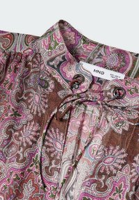 Col de chemise avec motif paisley rose, marron et vert, doté d'un cordon de serrage et d'une étiquette de marque MNG visible avec les informations de taille.
