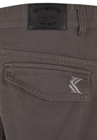 Grå denimjeans med et lærbelte merke, akkompagnert av en liten brodert logo på baklommen. Har detaljert søm.