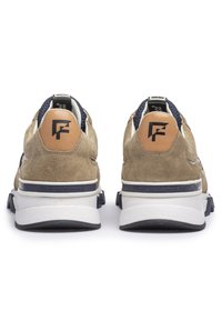 Brązowe zamszowe sneakersy z białą środkową podeszwą, granatowymi akcentami i czarną gumową podeszwą zewnętrzną. Na pięcie i języku widoczne logo.