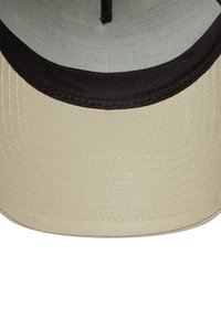 Beige Mütze mit schwarzem Schirm, aus einem strukturierten, strapazierfähigen Stoff. Das Innere ist mit einem grauen Netzmaterial ausgekleidet. Die Nähte sind entlang der Kanten sichtbar.