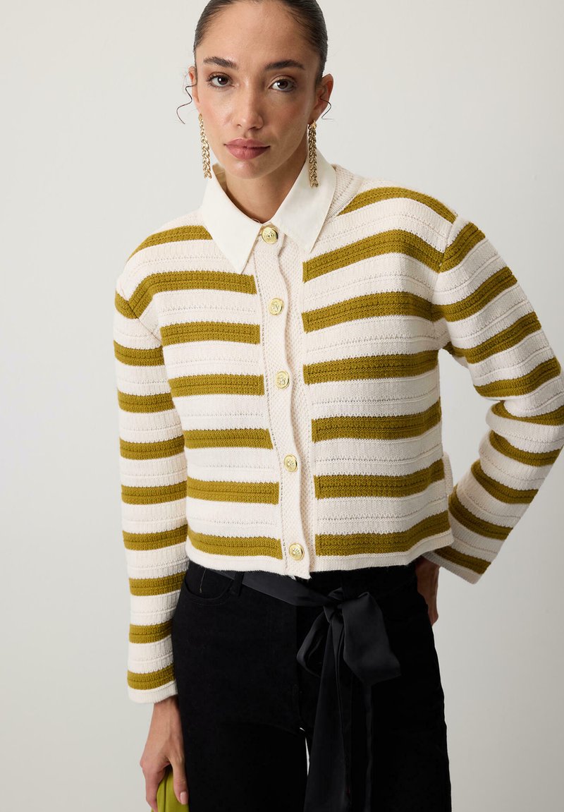 Gebreide cardigan met groen en witte strepen, sluiting met knopen aan de voorkant en een witte kraag. Geweven stof met ribbels aan de manchetten.