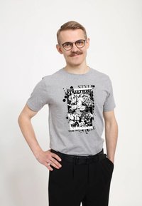 Šedé bavlněné tričko s černobílým grafickým tiskem, zahrnujícím text, abstractní tvary a design s kapkami na přední straně.