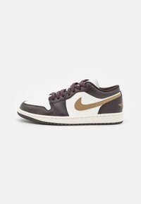 Tenisky s bílým koženým svrškem, hnědými koženými akcenty, béžovým logem "Swoosh", kulatými tkaničkami a texturovanou gumovou podrážkou.