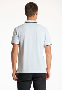 Camisa polo de color azul claro con mangas cortas, con un borde oscuro en contraste en el cuello y las mangas, hecha de una tela suave y presenta un corte clásico.