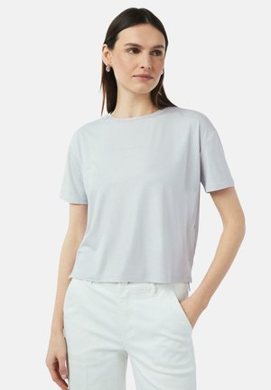 Light gray, short-sleeve t-shirt with a loose fit, round neckline, and subtle sheen. Minimalist design, featuring a small logo detail on the front.