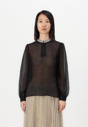 Svart transparent bluse med lange pufferm, detaljert krage med utsmykkinger, og en åpning foran med nøkkelhull. Teksturert stoff med subtile striper.