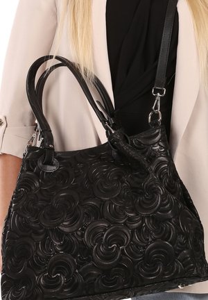 Sac à main en cuir noir avec des motifs en relief semblables à des roses, poignées doubles, bandoulière réglable et accents en métal argenté. Design texturé et structuré.