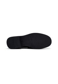 Suela de zapato de vestir negro con áreas de agarre lisas y ligeramente texturizadas, mostrada desde la vista inferior sobre un fondo blanco.