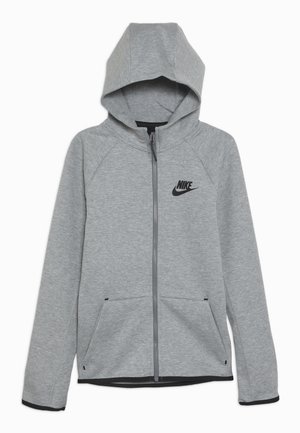 Haut de sweat à capuche gris zippé fabriqué à partir d'un tissu léger, avec une capuche, des manches longues, des poches latérales et un logo Nike noir sur la poitrine.