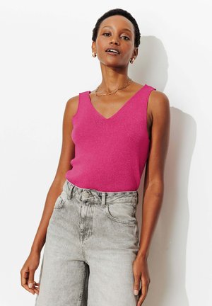 Haut sans manches fuchsia avec un col en V, texture côtelée. Associé à un jean en denim gris clair taille haute. Collier chaîne en or minimaliste.