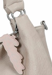 Bolso de mano de cuero beige con acabado texturizado, con herrajes plateados y un charm en forma de hoja rosa adjunto al asa.