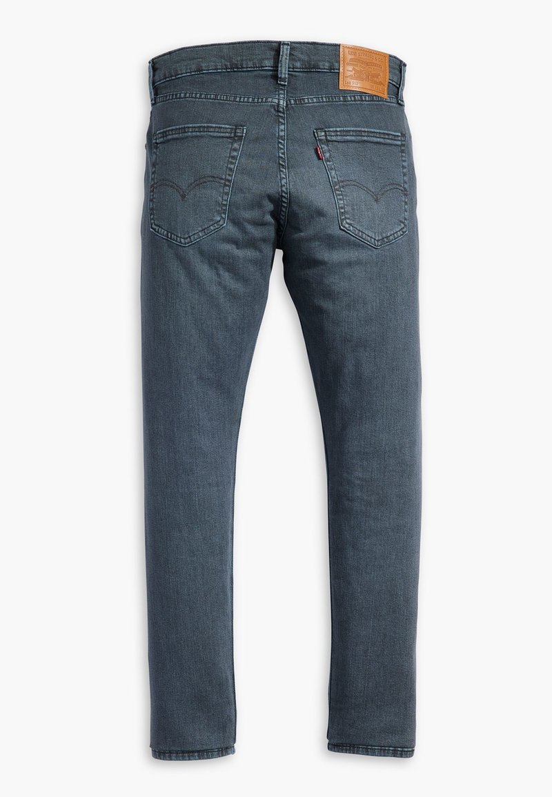 Dunkelblaue Jeans mit geradem Schnitt, ausgestattet mit einem Leder-Brandaufnäher an der Taille, zwei Gesäßtaschen und dezenten Nähten.
