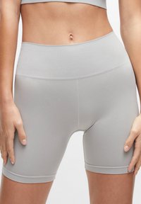 Šedé šortky s vysokým pasem vyrobené z hladké elastické tkaniny, které se přizpůsobují postavě a mají bezešvý design, ideální pro aktivní nošení.