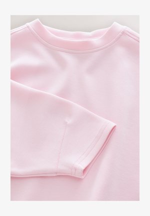 Gaiši rozā džemperis ar apaļu kakla izgriezumu un garām piedurknēm. Mīksta tekstūra ar rūpīgām šuvēm apkārt apkaklei un piedurknēm.