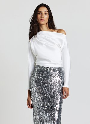 Schulterfreies weißes Satintop kombiniert mit einem silbernen Paillettenrock, der eine figurbetonte Silhouette und durchgehend reflektierende Textur aufweist.
