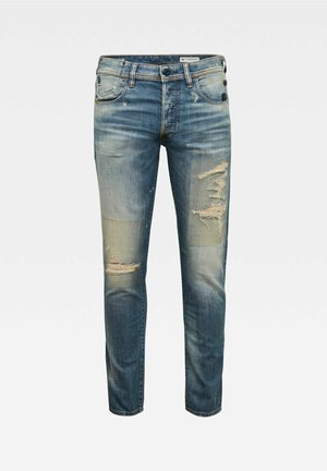 Blaue Denim-Jeans mit schmaler Passform, abgenutzten Stellen an Oberschenkeln und Knien sowie einem ausgewaschenen Effekt im gesamten Stoff.