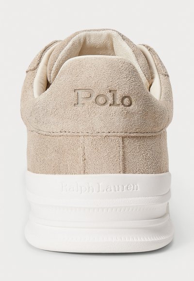 Talons de sneaker en suède beige avec "Polo" brodé et "Ralph Lauren" en relief sur la semelle blanche.