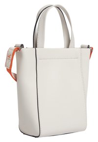 Bílá koženková taška přes rameno s černými detaily. Má krátké ucha a odnímatelný ramenní popruh s vzorem v oranžové a béžové barvě.