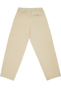 Beige Baumwoll-Jogginghosen mit elastischem Bund, ausgestattet mit einer Gesäßtasche und farblich gestreiftem Akzent. Gerader, schmal zulaufender Beinverlauf.