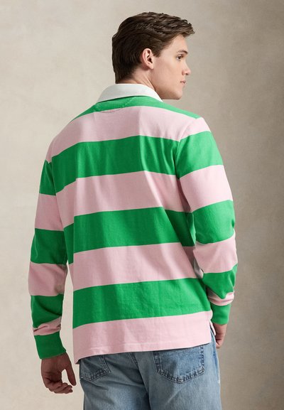 Μπλούζα πόλο με μακριά μανίκια, με εναλλασσόμενες οριζόντιες πράσινες και ροζ ρίγες, λευκό γιακά και άνετη εφαρμογή, συνδυασμένη με ανοιχτόχρωμο τζιν.