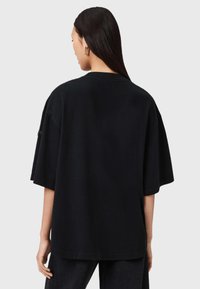 Černé oversized tričko s krátkým rukávem, vyrobené z měkké látky. Má kulatý výstřih a bezešvé záda, což zajišťuje uvolněný střih.
