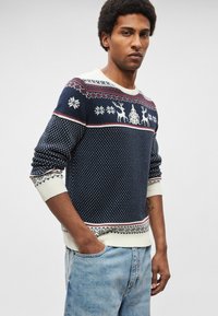 Tmavomodrý pletený sveter s bielymi vzormi sobov a snehových vločiek, rebrovaným golierom a manžetami, kontrastným krémovým lemom a geometrickými detailmi.