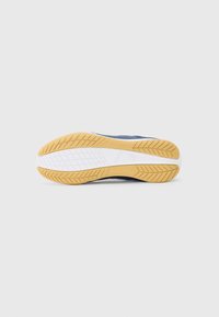 Suela de zapatilla deportiva con una suela exterior de goma amarilla texturizada, una entresuela blanca y una parte superior en azul marino con un acabado suave.