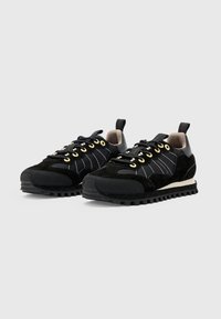 Sneaker neri con tomaia in suede e tessuto, occhielli dorati, cuciture bianche, suola testurizzata e battistrada in gomma nera.
