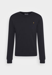 Sudadera negra de algodón, con un cuello redondo, mangas largas y un pequeño logotipo amarillo en el pecho. Textura suave con puños acanalados.