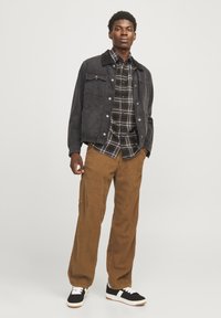Dark denim jacket with two front pockets, checkered shirt in black and brown, brown corduroy pants, and black sneakers with white accents.