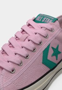 Ροζ sneaker από σουέντ με τιρκουάζ λεπτομέρειες, με επίπεδα κορδόνια, μεταλλικά γαντζάκια και σήμα με το λογότυπο στη γλώσσα. Υφή επιφάνειας με ορατές ραφές.