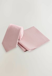 En lyserød mønstret slips rullet sammen med et matchende lommehåndklæde, begge lavet af tekstureret materiale med et geometrisk design.
