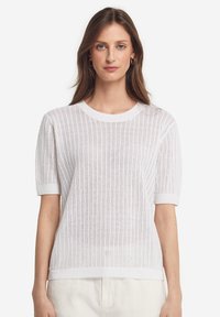 Hvid strikket kortærmet sweater med rund halsudskæring, der har et let, struktureret mønster samt ribbede kanter ved bund og ærmer.
