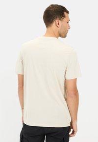 Lysbeige kortærmet t-shirt med rund halsudskæring og afslappet pasform, vist fra ryggen med et glat tekstureret stof.