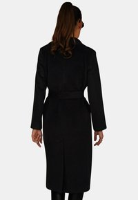 Czarny, dopasowany płaszcz z długimi rękawami, podkreśloną talią, detalem paska oraz gładką fakturą. Charakteryzuje się prostym krojem i brakiem widocznych zapięć.