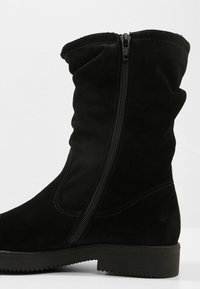 Černé semišové vysoké boty po kolena se zipem na boku, které mají jemnou texturu, zaoblený vršek a plochou gumovou podrážku. Hladké švy jako akcenty.