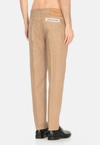 Pantaloni beige a righe realizzati in tessuto leggero. Presentano due tasche posteriori, un'etichetta logata in vita e una vestibilità sartoriale con una forma dritta.