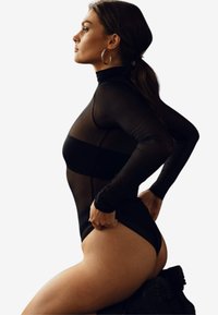Czarny bodysuit z długimi przezroczystymi rękawami, wysokim kołnierzem i dopasowanym fasonem. Posiada solidną wstawkę w talii i gładką fakturę.