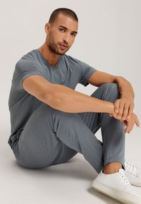 T-shirt grigio a scollo a V e pantaloni abbinati realizzati in morbido tessuto, progettati per il massimo comfort. Sneakers bianche completano il look casual.