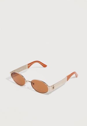 Lunettes de soleil ovales avec montures en métal doré et verres teintés marron, dotées d'embouts de branches en plastique orange et de larges branches métalliques.
