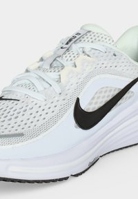Λευκό αθλητικό παπούτσι Nike με μαύρο λογότυπο, επάνω μέρος από αεριζόμενο διχτυωτό υλικό, λευκά κορδόνια και μαξιλαρωμένη σόλα με την ένδειξη "ComfRide."